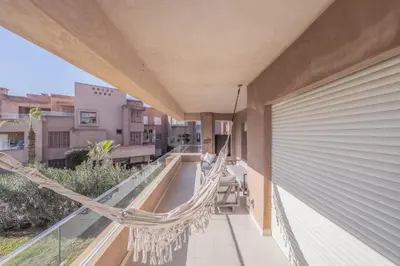 a hammock on the balcony of a house at Family Apartment 3 Bedrooms Prestigia with Pool in Marrakech