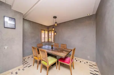a dining room with a wooden table and chairs at Family Apartment 3 Bedrooms Prestigia with Pool in Marrakech