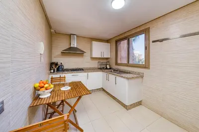 a kitchen with a table with a bowl of fruit on it at Family Apartment 3 Bedrooms Prestigia with Pool in Marrakech