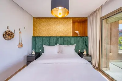 a bedroom with a large bed with a green headboard at Family Apartment 3 Bedrooms Prestigia with Pool in Marrakech