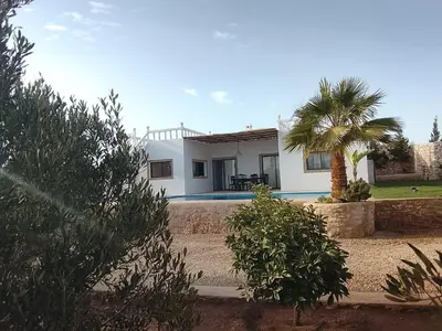 a white house with a palm tree in front of it at Alexandra Nomade - Maison de transition & séjours de répit in Marrakech