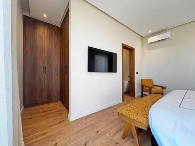 a bedroom with a bed and a tv on a wall at 4-Suite Villa, Private Pool at Jade Garden in El Rhechat
