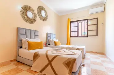 a bedroom with two beds and a mirror on the wall at bel appartement très calme in Marrakech