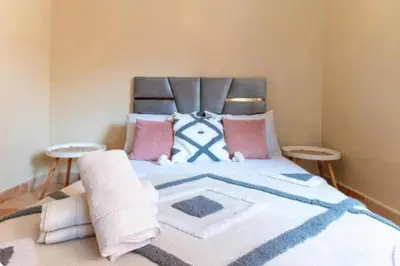 a bedroom with a large bed with pink and blue pillows at bel appartement très calme in Marrakech