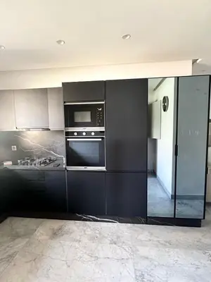 a kitchen with black cabinets and a microwave at Villa du Lac 4 suites in Prestigia in Marrakech