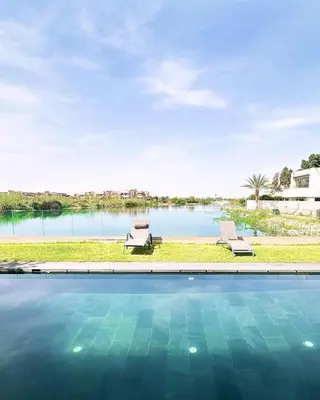 a swimming pool with a view of a body of water at Villa du Lac 4 suites in Prestigia in Marrakech