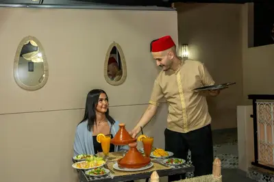 a man and a woman standing next to a table with food at Riad Dar Al Ghali in Marrakech