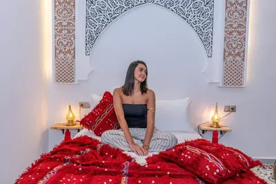 a woman sitting on a bed in a room at Riad Dar Al Ghali in Marrakech