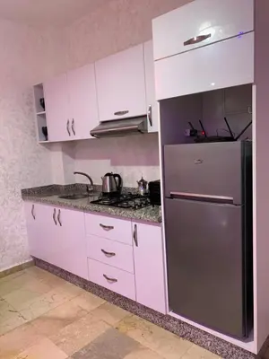 a kitchen with white cabinets and a stainless steel refrigerator at Studio moderne et calme à Guéliz in Marrakech