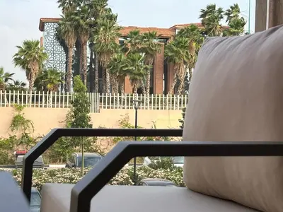 a white couch sitting on a balcony with palm trees at Apartment with swimming pool full air-conditioned in Marrakech