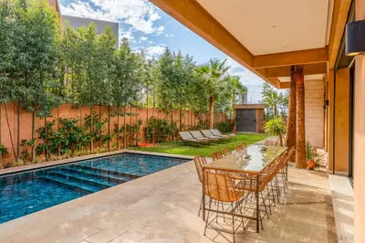 a patio with a table and chairs next to a swimming pool at Sublime Villa in Agdal Elevator with heated pool in Marrakech