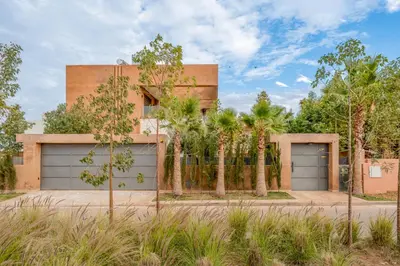 a house with two garage doors and palm trees at Sublime Villa in Agdal Elevator with heated pool in Marrakech