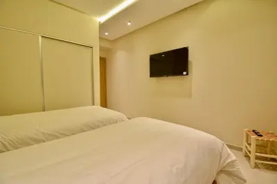 two beds in a room with a tv on the wall at Le Petit Medina - 4prs - Wifi - Semlalia in Marrakech