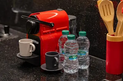 a red coffee maker with two cups and water bottles at Le Grand Jazzy in Marrakech