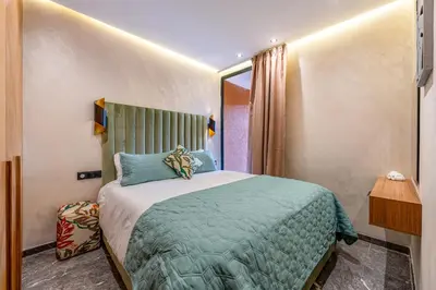 a bedroom with a bed with a green comforter at Le Grand Jazzy in Marrakech