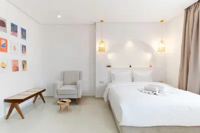 a white bedroom with a large bed and a chair at Studio Horizon Marrakech Station in Marrakech