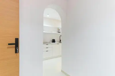 a kitchen with white cabinets and an arched doorway at Studio Horizon Marrakech Station in Marrakech