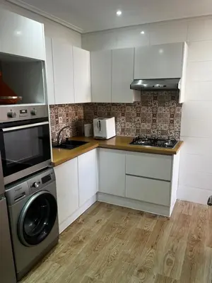 a kitchen with white cabinets and a washer and dryer at L'Oasis Des Amis in Marrakech