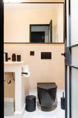 a bathroom with a black toilet and a mirror at Majorelle Modern A Unique Green Cocoon in Marrakech