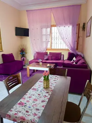 a living room with a table and purple furniture at Spacieux Appart 2 chambres 6 Pers 12min Aéroport in Marrakech