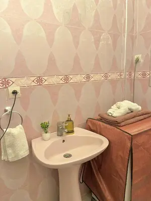 a bathroom with a white sink and pink and white wallpaper at Spacieux Appart 2 chambres 6 Pers 12min Aéroport in Marrakech