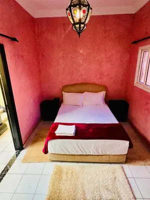 a bedroom with a bed with red walls and a chandelier at Lina Stay Riad Alkaria Assiyahia in Marrakech