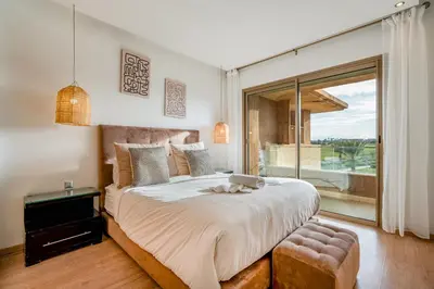 a bedroom with a large bed and a large window at Cozy Apt with pool, Wifi, parking, Golf Views & Sunny Private Balcony in Marrakech