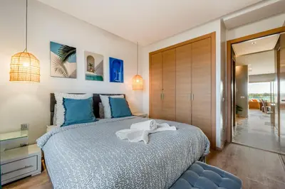 a bedroom with a large bed with blue pillows at Cozy Apt with pool, Wifi, parking, Golf Views & Sunny Private Balcony in Marrakech