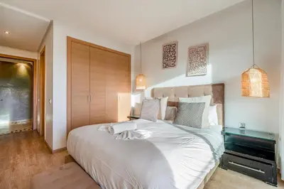 a bedroom with a large bed with white sheets at Cozy Apt with pool, Wifi, parking, Golf Views & Sunny Private Balcony in Marrakech