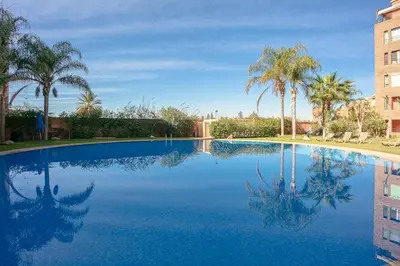 a swimming pool with palm trees and a building at The Good Mood - Hivernage Marrakech in Marrakech