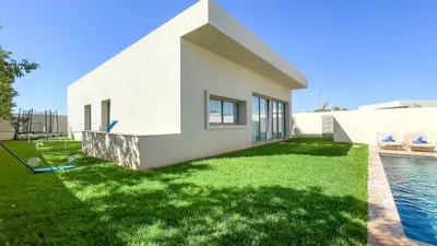 a white house with a swimming pool and a yard at Beautiful Bianca villa with heated pool in Marrakech