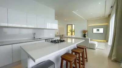 a white kitchen with a counter and stools in it at Beautiful Bianca villa with heated pool in Marrakech