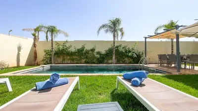 a swimming pool with two blue pillows in a yard at Villa Alya with heated pool in Marrakesh in Marrakech