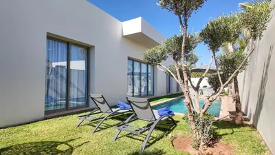 a yard with three chairs and a swimming pool at Villa DALIA in Marrakech