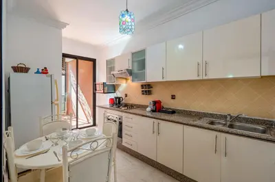 a kitchen with white cabinets and a table and a sink at Relaxing stay with pool & secure parking in Marrakech