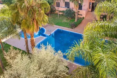 an aerial view of a swimming pool in a yard with palm trees at Relaxing stay with pool & secure parking in Marrakech