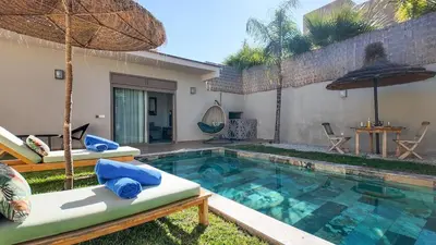 a swimming pool with two chairs and an umbrella at Aman Bungalow - heated pool, not overlooked in Marrakech