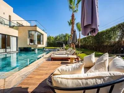 a swimming pool with white couches and an umbrella at Le Palais Zahira & Palais Mahora 2 villas in Marrakech