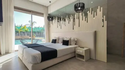 a bedroom with a large bed and a chandelier at Beautiful AWAL Villa, 6 suites & heated pool in Marrakech