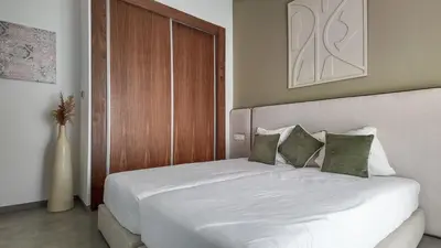 a bedroom with a white bed with green pillows at Beautiful AWAL Villa, 6 suites & heated pool in Marrakech
