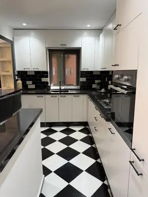 a white kitchen with a black and white checkered floor at Beautiful modern triplex in Qariya Sayhia in Marrakech