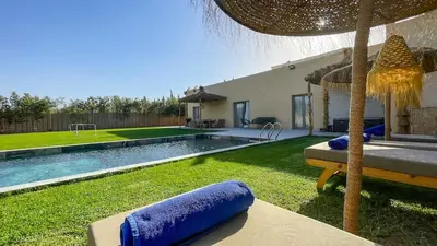 a backyard with a swimming pool and an umbrella at Villa JAMAL with heated pool in Marrakech in Marrakech