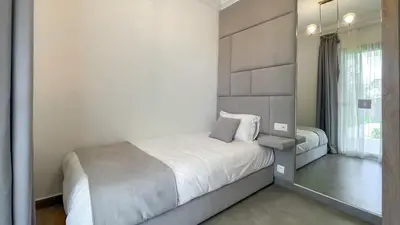 a white bedroom with a bed and a mirror at Villa JAMAL with heated pool in Marrakech in Marrakech