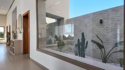 a large glass window in a hallway with cactus at Villa Céleste avec piscine chauffée in Marrakech