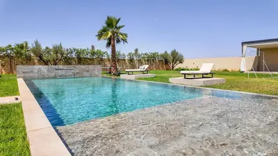 a swimming pool in a yard with two benches at Villa Delina heated pool not overlooked in Marrakech