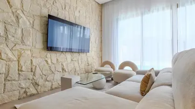 a living room with a couch and a tv on a stone wall at Wintering Bungalow-Heated pool not overlooked in Marrakech
