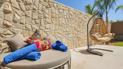 a chair and a table with pillows on a patio at Targa Bungalow - Heated pool, not overlooked in Marrakech