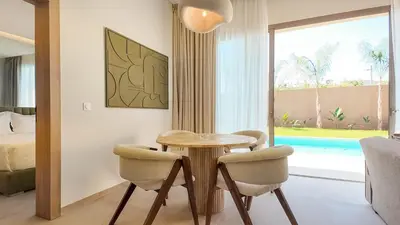 a dining room with a table and chairs and a bedroom at Palm Grove Bungalow - Heated pool, not overlooked in Marrakech