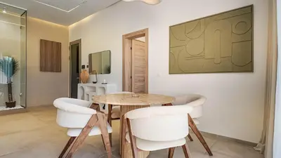 a dining room with a wooden table and white chairs at Palm Grove Bungalow - Heated pool, not overlooked in Marrakech