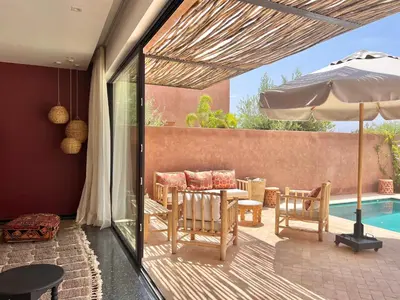 a patio with a table and an umbrella and a pool at Villa Bohō - 4 suites in El Rhechat